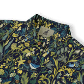 Shirt featuring dense foliage and bird designs on a deep-colored background.