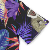 Close-up of a shirt sleeve showcasing a colorful tropical design with purple and blue leaves, a monkey, and other vibrant elements on a dark background.