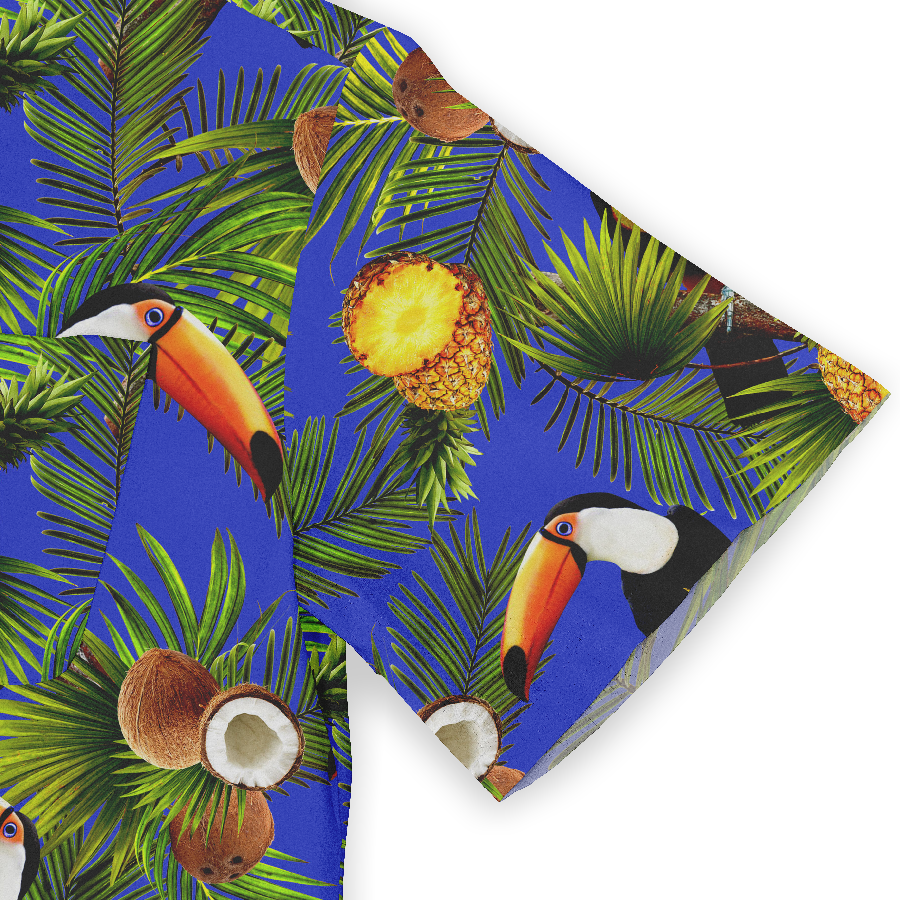 Close-up of a Hawaiian shirt sleeve, featuring a vibrant design of palm leaves, toucans, coconuts, and pineapples on a blue background.