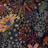 A close-up of a fabric design with a vibrant mix of flowers and leaves in colors like orange, red, yellow, green, and white on a dark background.