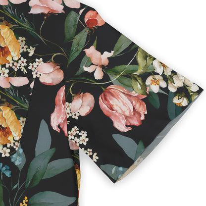 Close-up of a shirt sleeve with a black fabric featuring a detailed floral print, including pink, white, and orange flowers and green leaves.