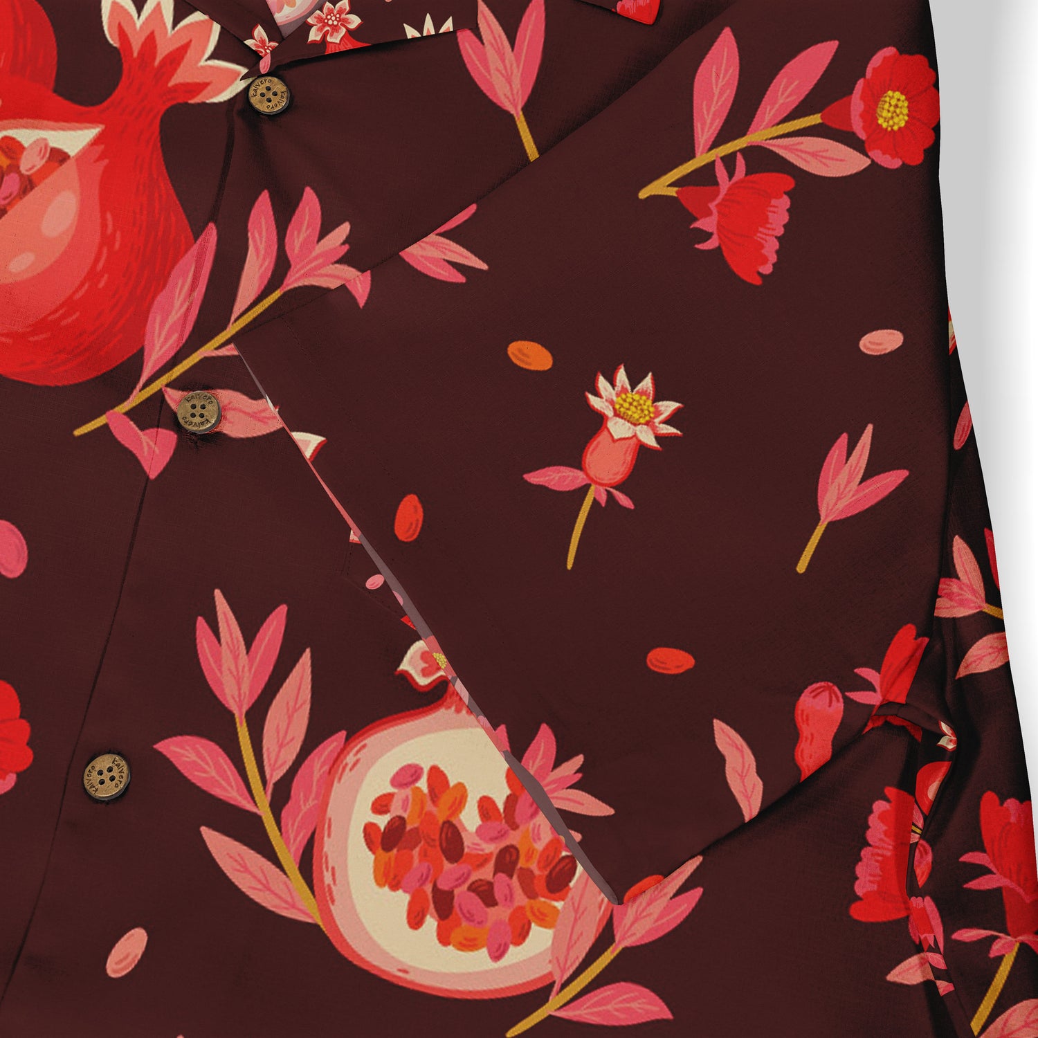 Close-up of a Hawaiian shirt pocket with a pomegranate and floral pattern in red and pink tones on a deep burgundy background, featuring brown buttons.​