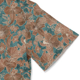 Close-up of a Hawaiian shirt sleeve with a floral pattern in brown and teal tones.