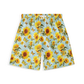 A pair of shorts featuring a vibrant design of large, bright yellow sunflowers and orange butterflies scattered across a light blue background, creating a cheerful and summery look.