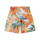 A pair of shorts featuring a vibrant design with cranes standing amidst tropical foliage, including large green leaves and sunflowers. The background is an orange and yellow sunset sky with soft clouds, creating a warm and serene atmosphere.